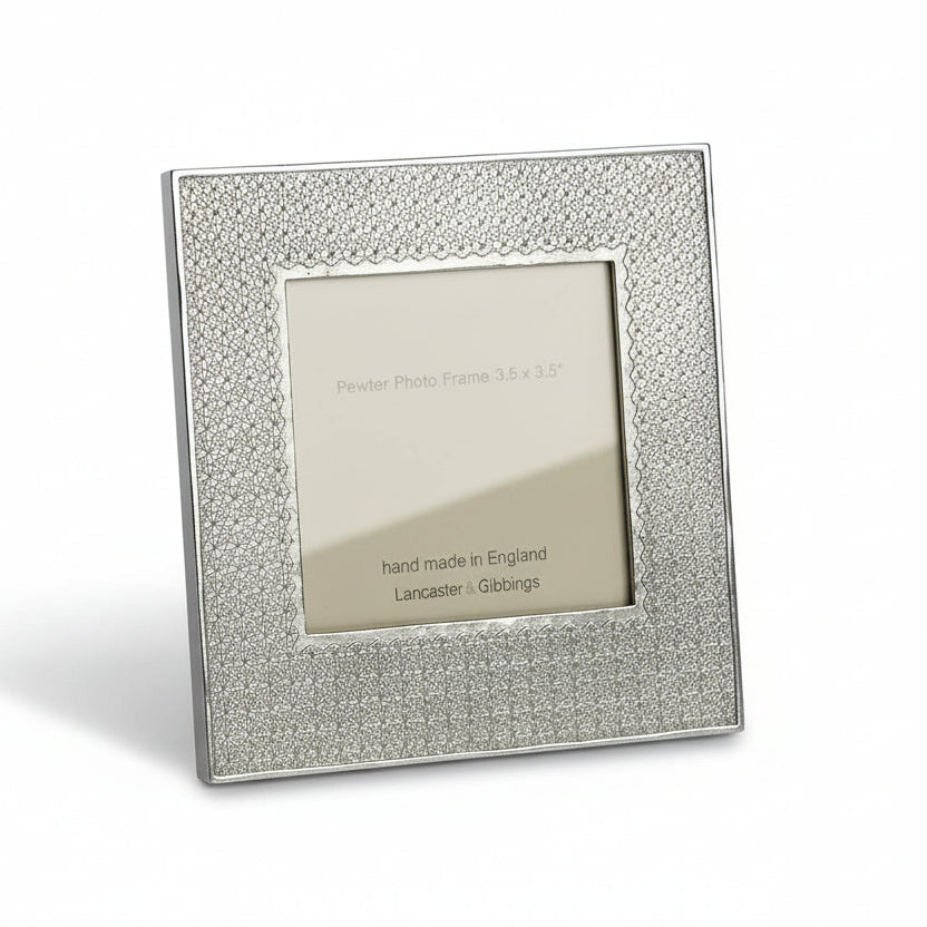 A pewter-colored metal picture frame with a geometric design around the photo window.